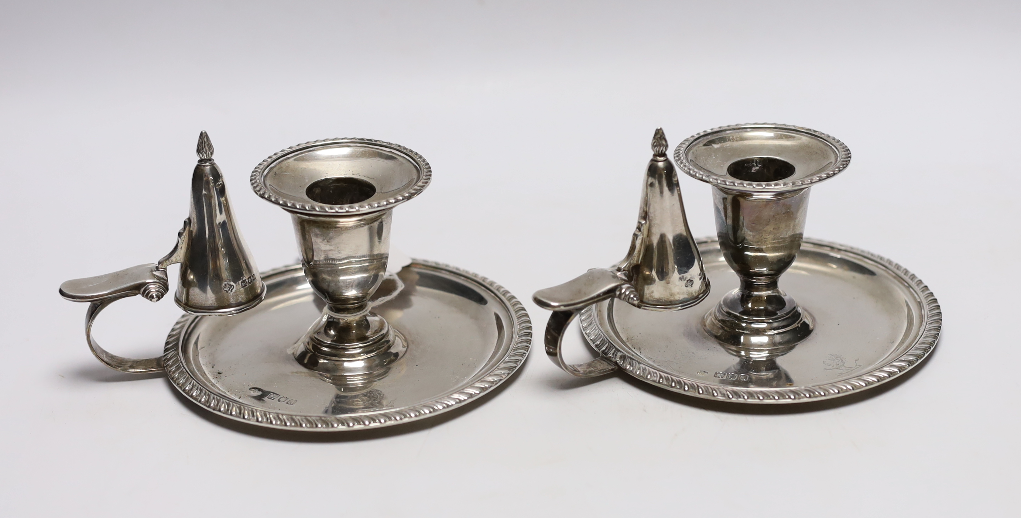 A pair of late Victorian silver chambersticks, with gadrooned borders and matching extinguishers, William Hutton & Sons, London, 1896, base diameter 13.2cm, 18.3oz.